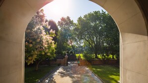 A view through an arched doorway into a garden with a paved path, trees, and a brick wall. - Wellington Hotel by Blue Orchid (London)