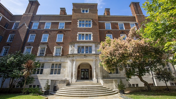 A large, multi-story brick building with a central entrance, surrounded by a well-maintained lawn and trees. - Wellington Hotel by Blue Orchid (London)