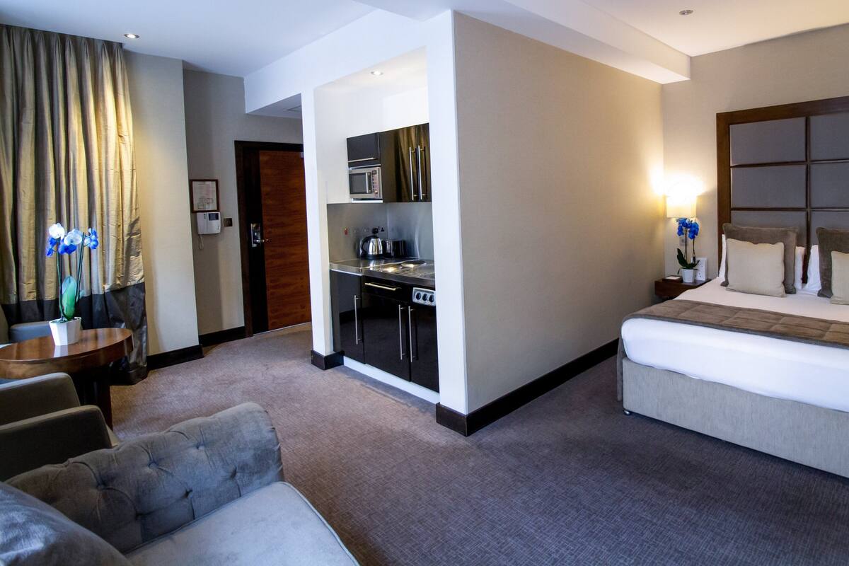Una habitación de hotel con cama, sofá, kitchenette y baño.