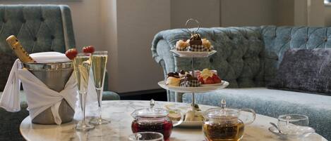 Ein Marmortisch mit einer Champagnerflasche, Gläsern, einer mehrstöckigen Kuchenplatte und Teeservice.