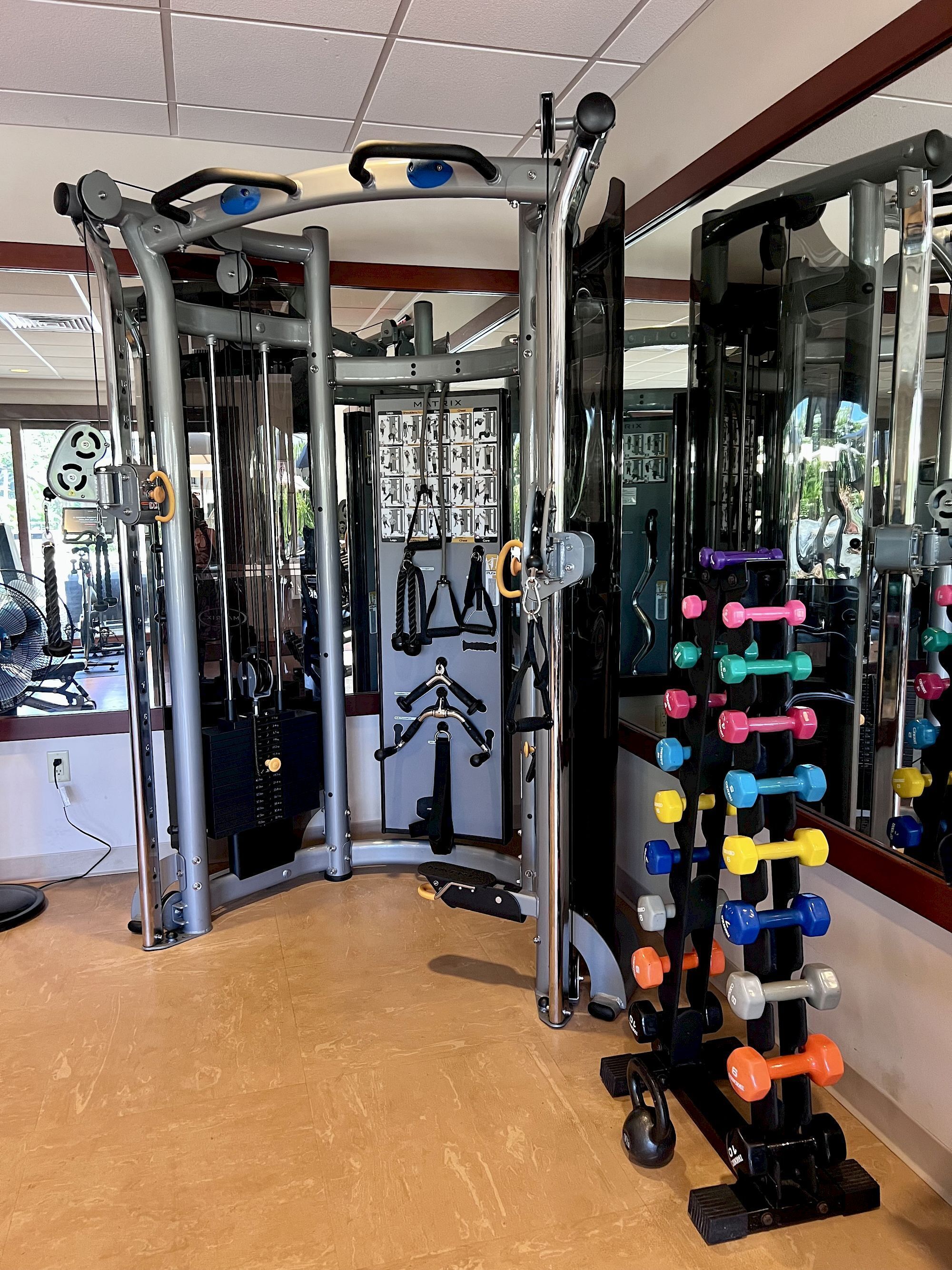 A gym with a variety of exercise equipment, including a multi-gym station, weight racks, and a mirror.