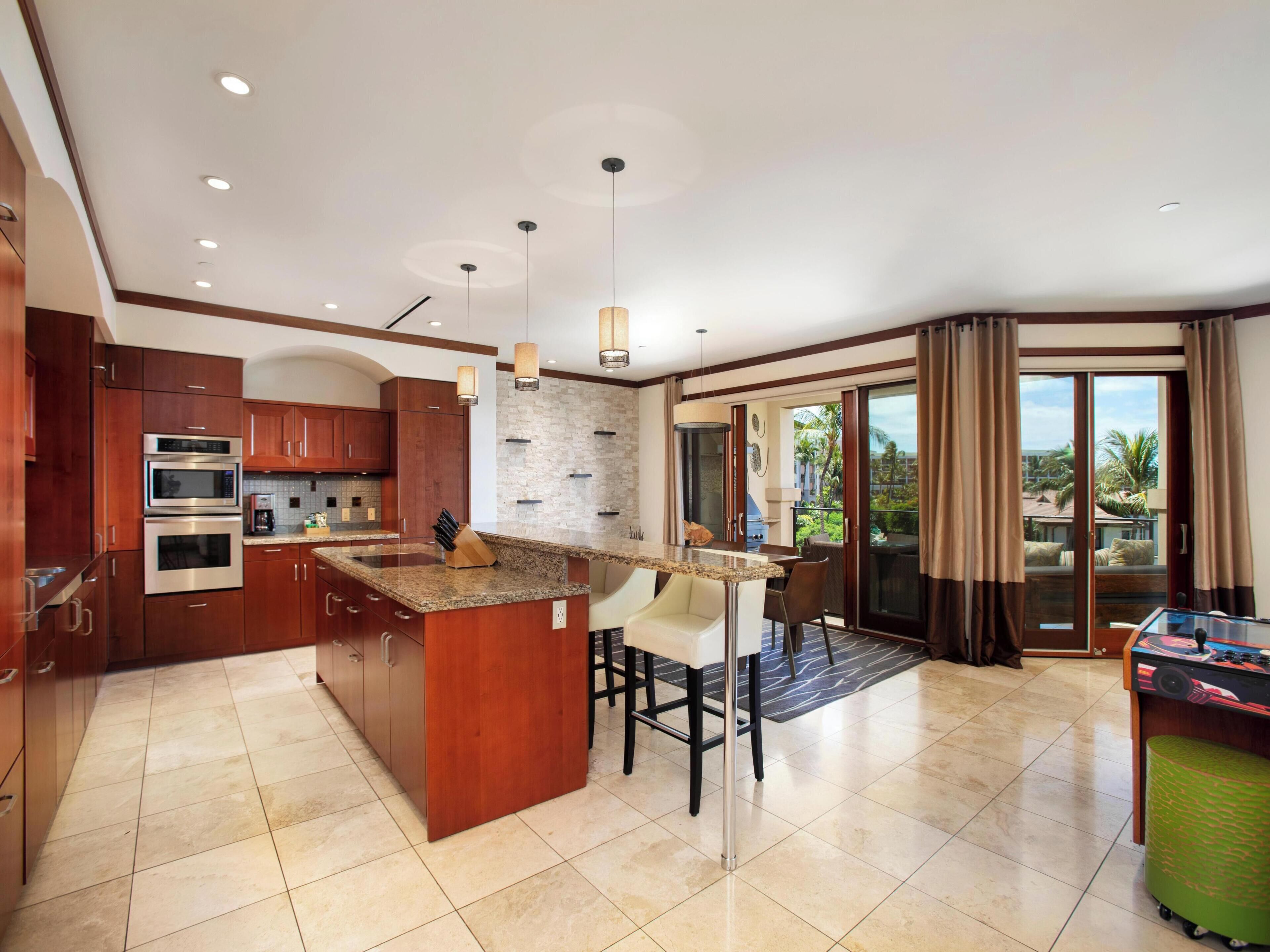 A modern kitchen with granite countertops, stainless steel appliances, and a central island with bar stools.