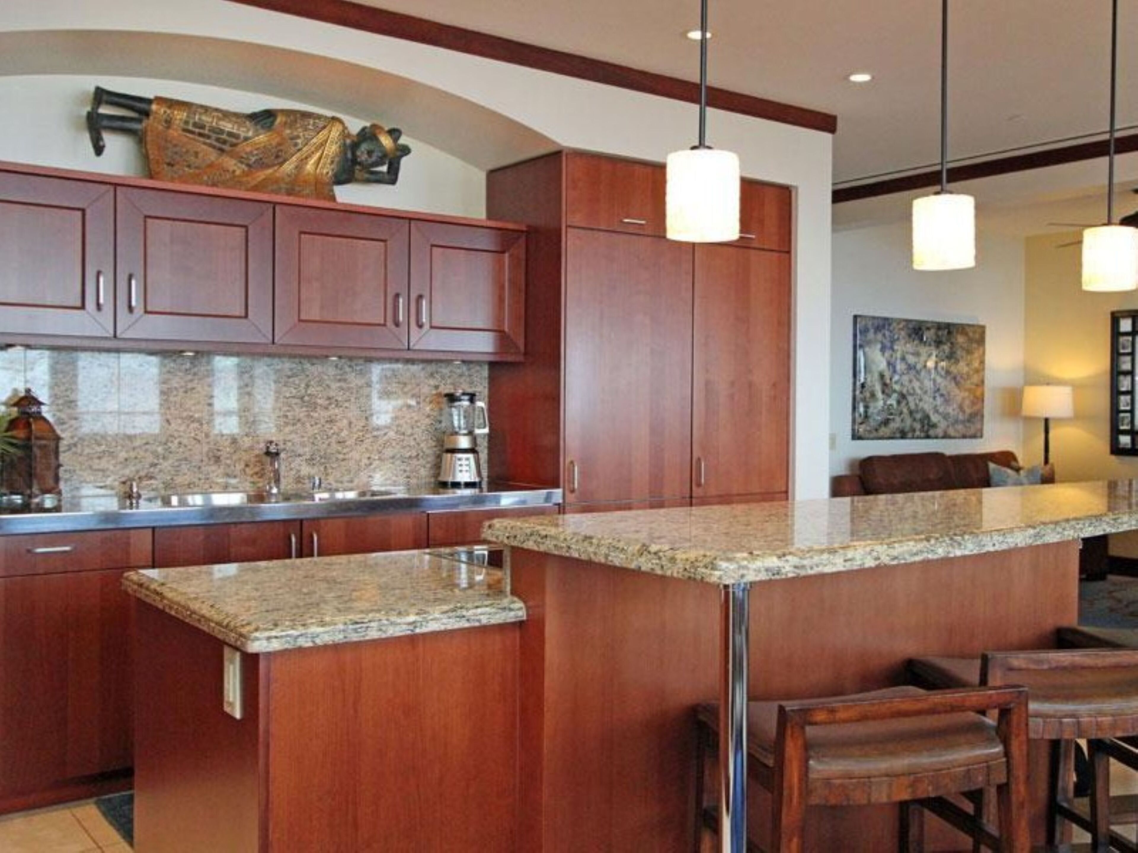 A kitchen with granite countertops, wooden cabinets, and pendant lighting.