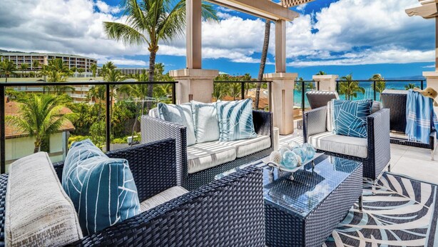 A rooftop lounge with wicker furniture, a glass coffee table, and a view of the ocean and palm trees. - Wailea Beach Villas (Kihei)