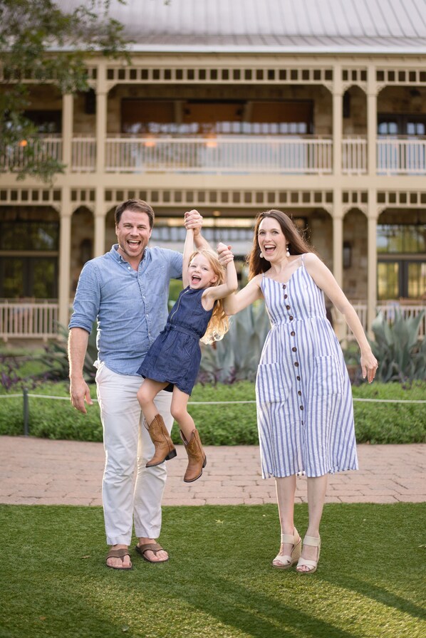 A family of three in front of a building with a balcony and a garden. - Hyatt Regency Lost Pines Resort and Spa (Cedar Creek)