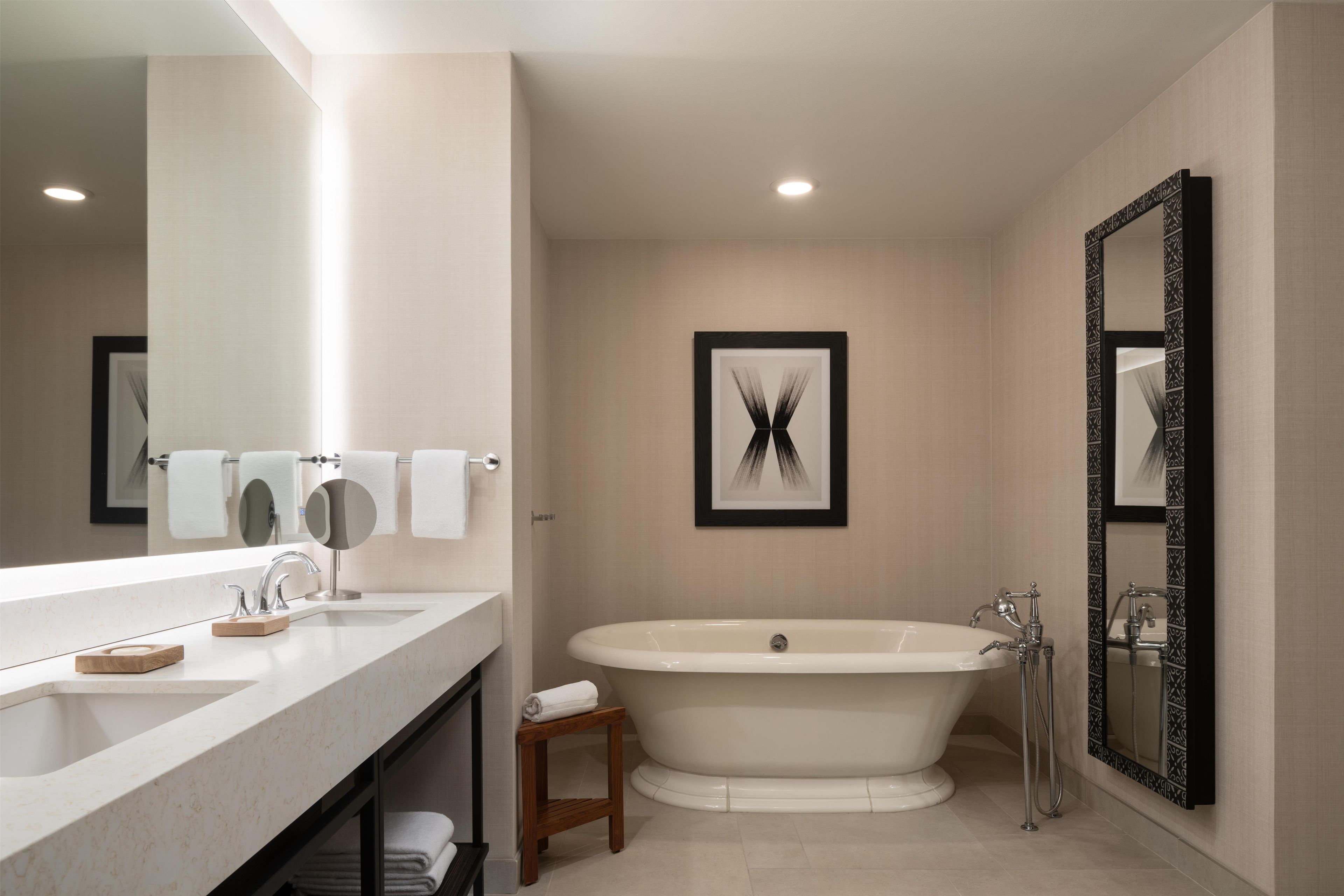 Une salle de bain moderne avec un grand miroir, une baignoire et un lavabo.