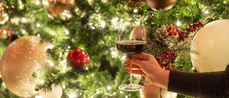 A hand holding a wine glass with a festive background.
