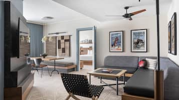 A modern living room with a sofa, a coffee table, a chair, a TV, and a ceiling fan.