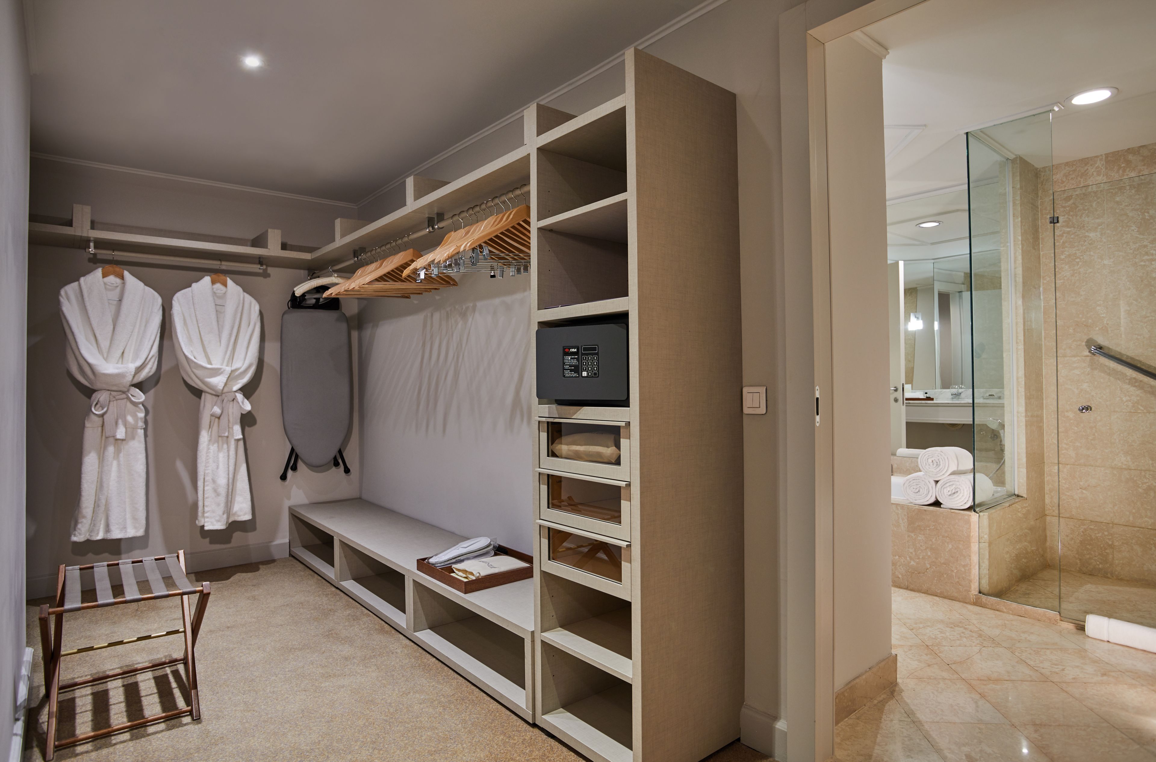A hotel bathroom with a walk-in shower, a robe drying rack, and a built-in storage unit.