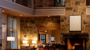 A spacious lobby with a stone wall, a fireplace, and a balcony.