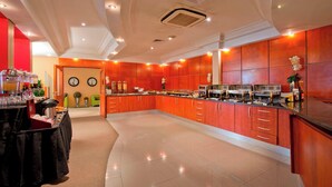 Une cuisine spacieuse avec des meubles de rangement rouges, un buffet et une horloge au mur.