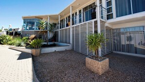 Un bâtiment moderne doté d’un balcon, d’un espace extérieur aménagé et de plantes en pot.