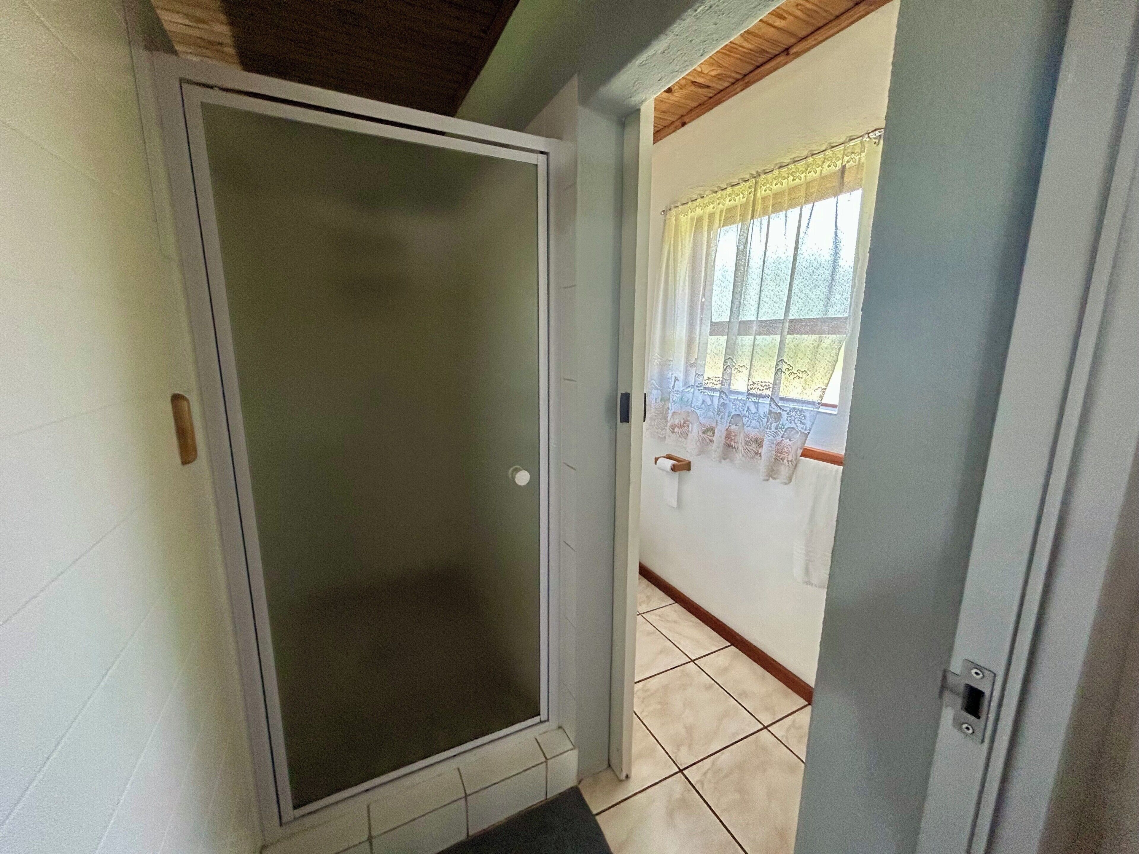 A room with a sliding glass door leading to a balcony, a window with a curtain, and a tiled floor.