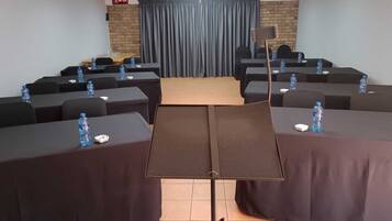 A conference room with tables, chairs, a podium, and a clock on the wall.