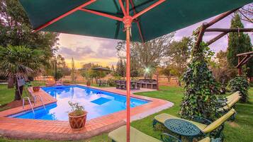 Una piscina al aire libre, sombrillas, sillones reclinables de piscina