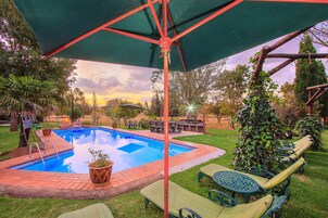 Una piscina al aire libre, sombrillas, sillones reclinables de piscina