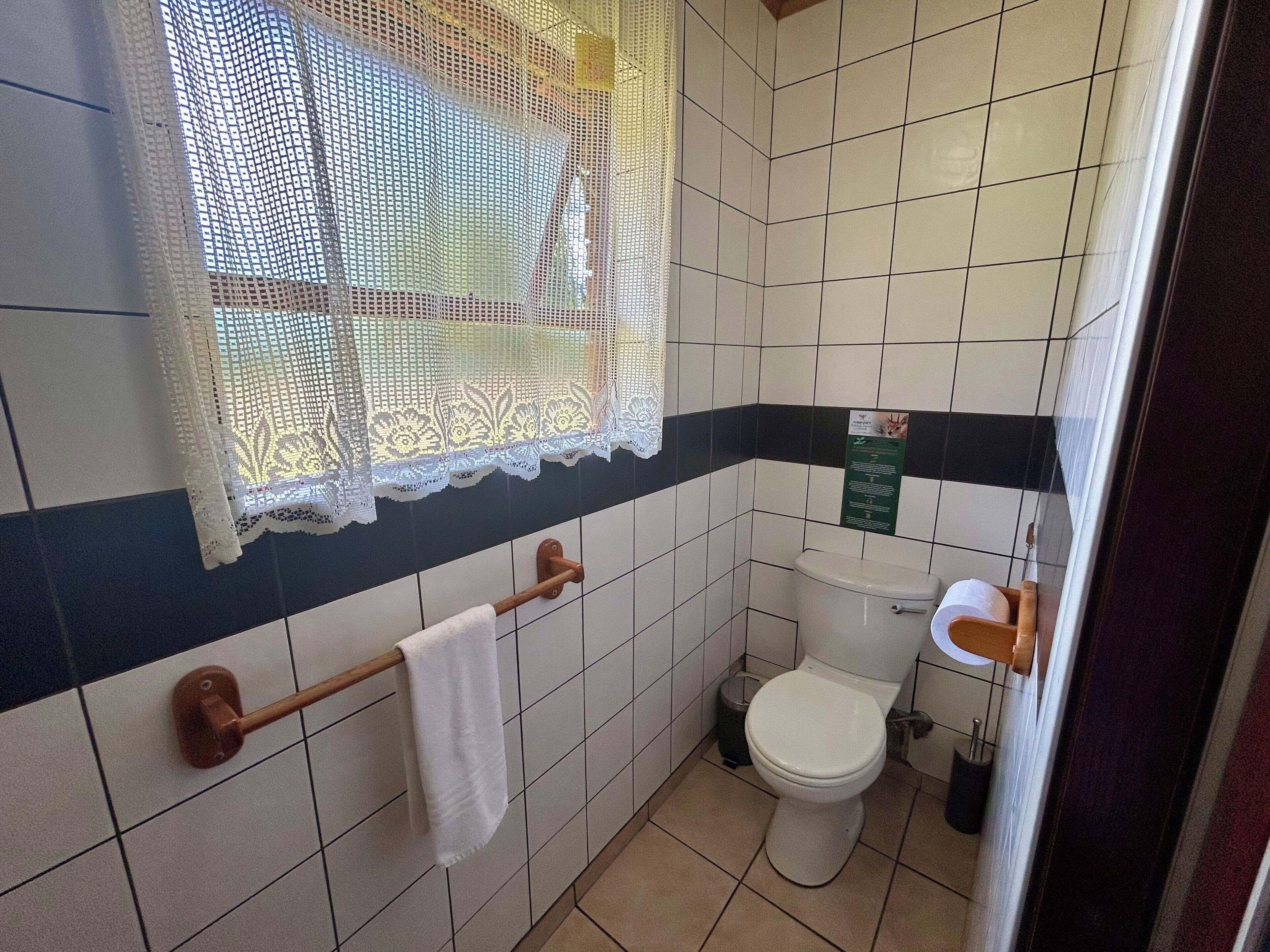 A bathroom with a toilet, sink, and a towel rack.