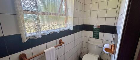 A bathroom with a toilet, sink, and a towel rack.