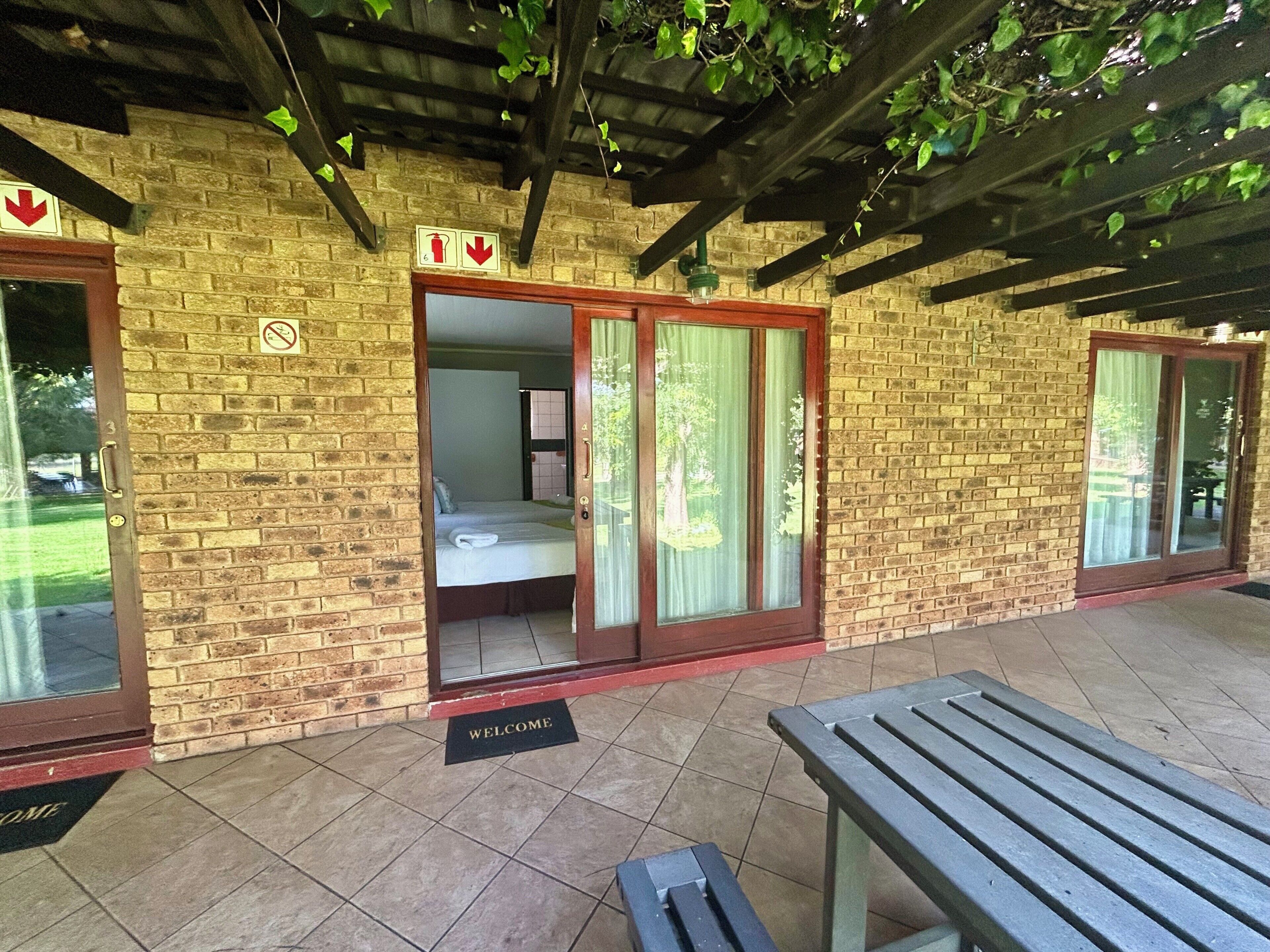 A brick building with a covered patio, a welcome mat, and a bench.