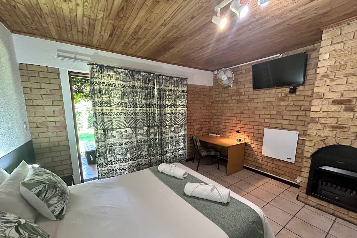 Un dormitorio con una cama, un escritorio, una silla, un televisor y una chimenea.
