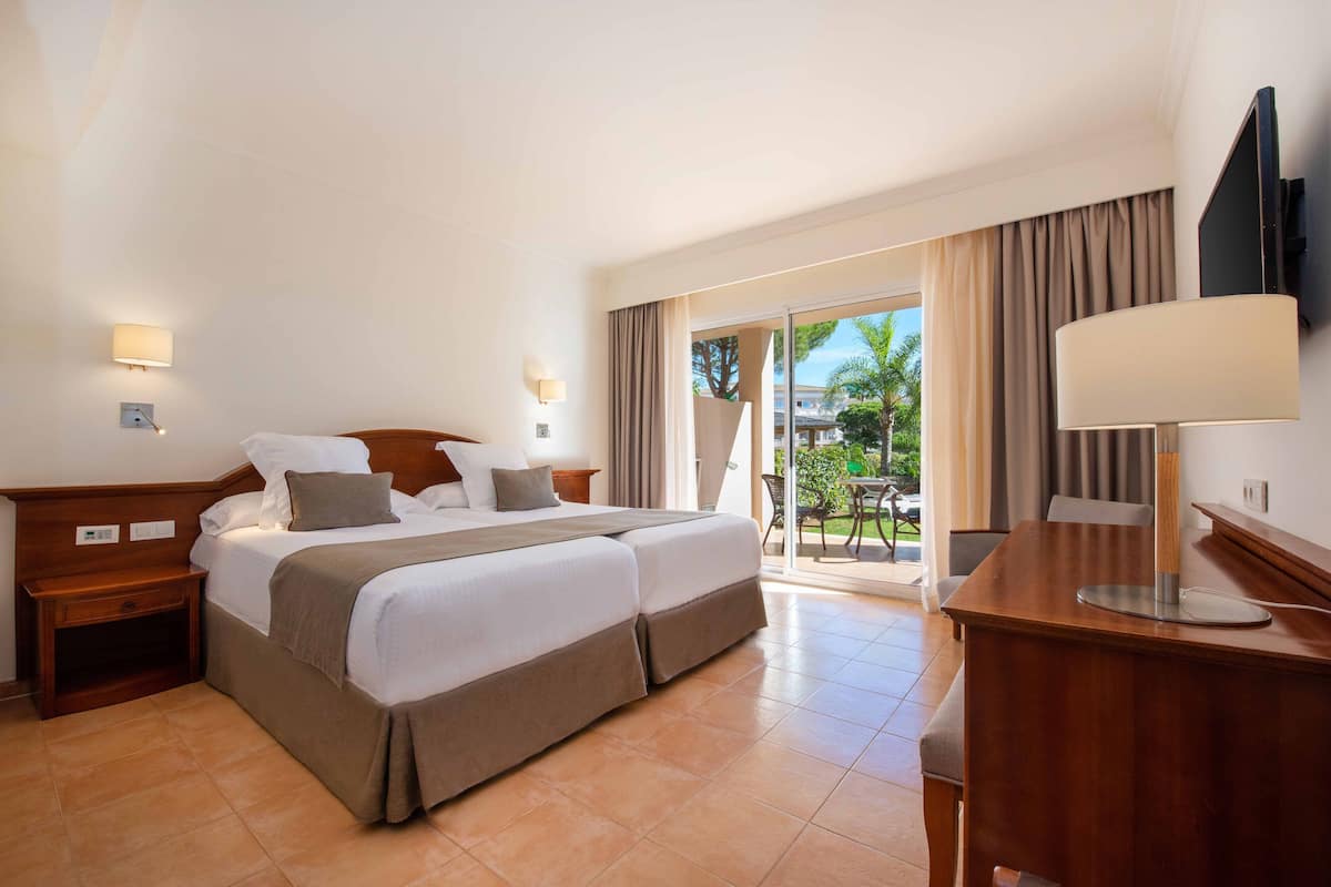 A hotel room with a bed, bedside tables, a desk, a chair, and a TV.