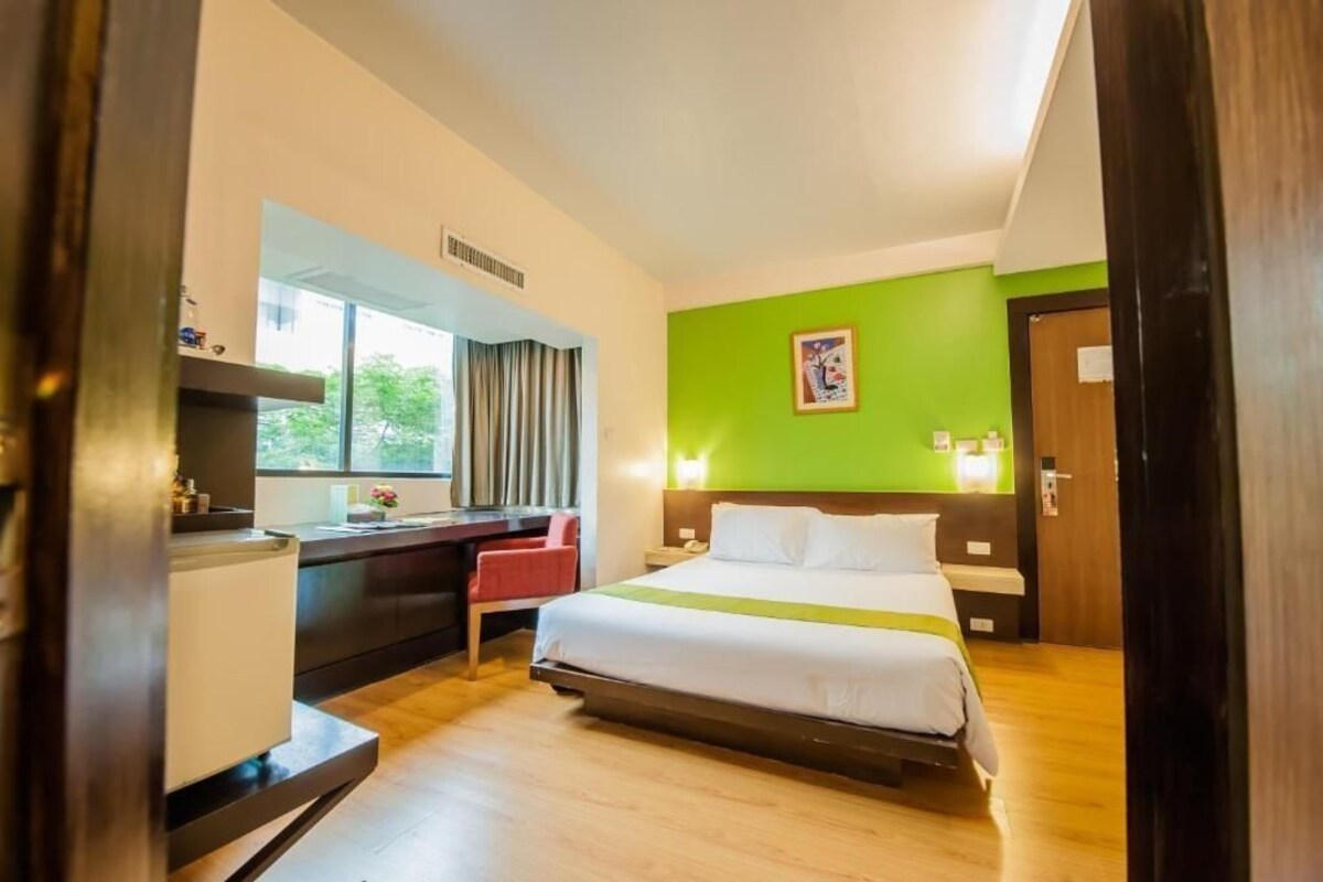 Een hotelkamer met een bed, bureau, stoel en raam.