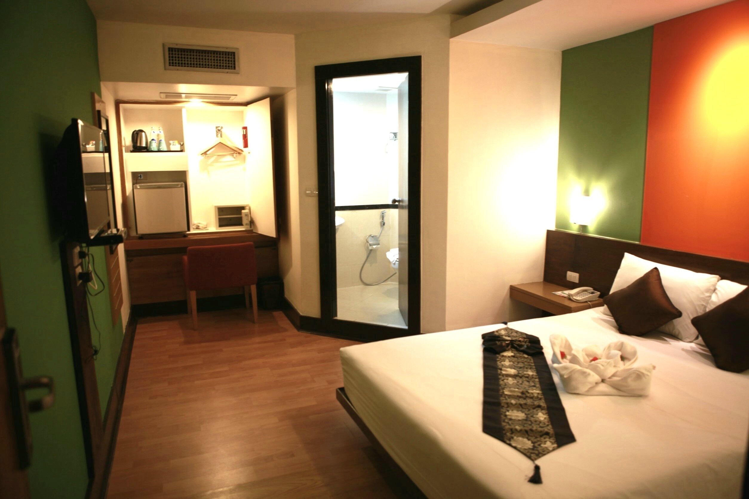 Une chambre d’hôtel équipée d’un lit, d’un bureau, d’un miroir, d’une douche et d’une kitchenette.