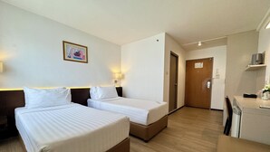 A hotel room with two beds, a wooden floor, a small kitchenette, and a door leading to another room. - Seasons Siam Hotel (Bangkok)