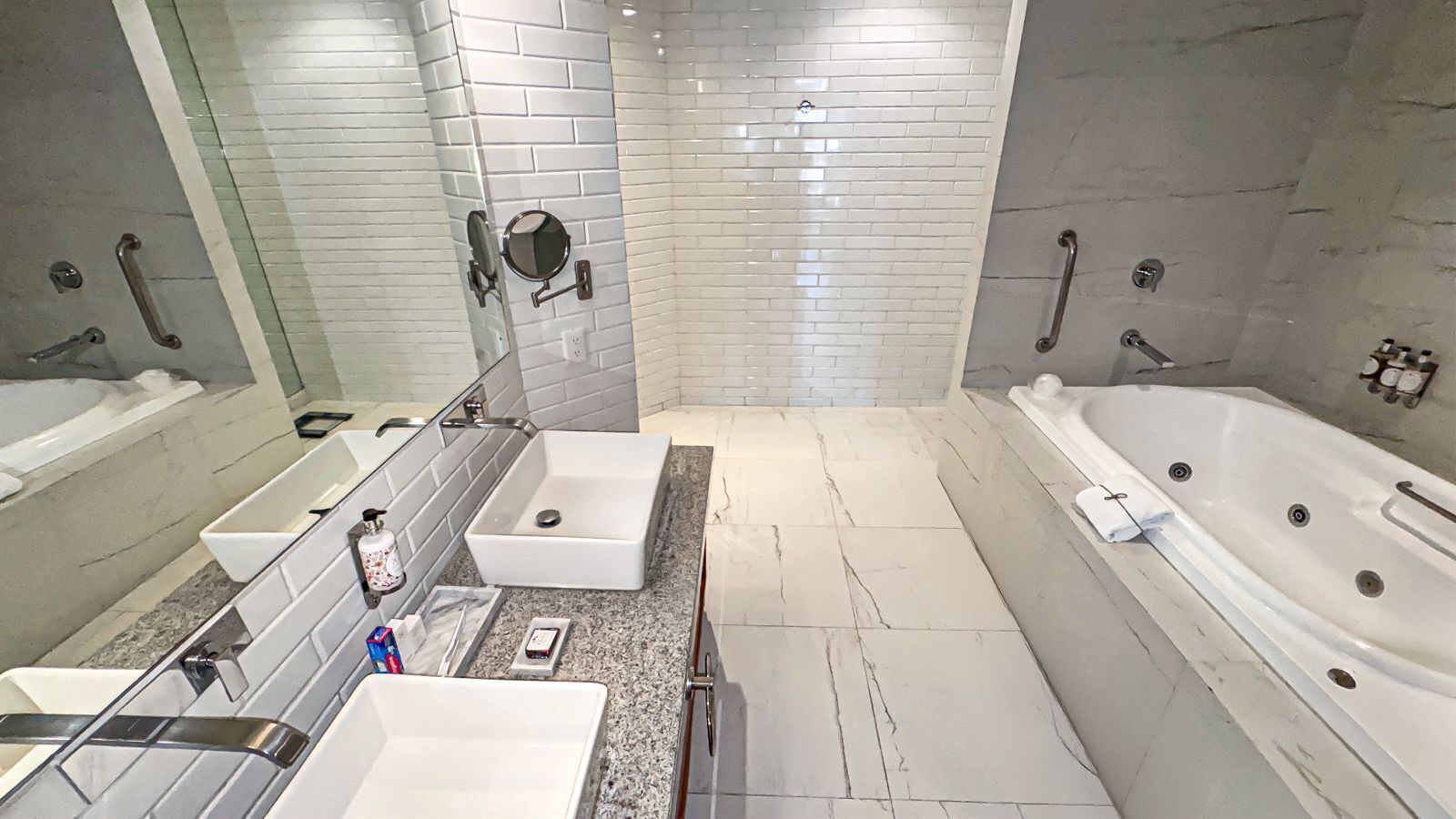 Ein modernes Badezimmer mit zwei Waschbecken, einer großen Badewanne und einem Spiegel.