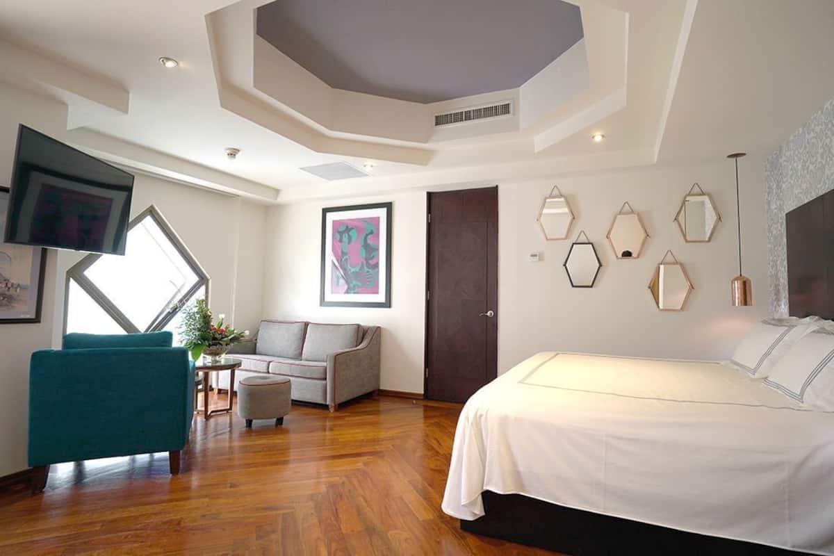 Une chambre d’hôtel moderne avec un grand lit, un canapé, une télévision et une fenêtre donnant sur un beau paysage.