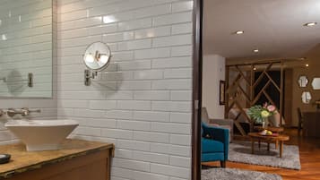 Un baño moderno con azulejos blancos tipo metro, un espejo redondo y un lavabo blanco.