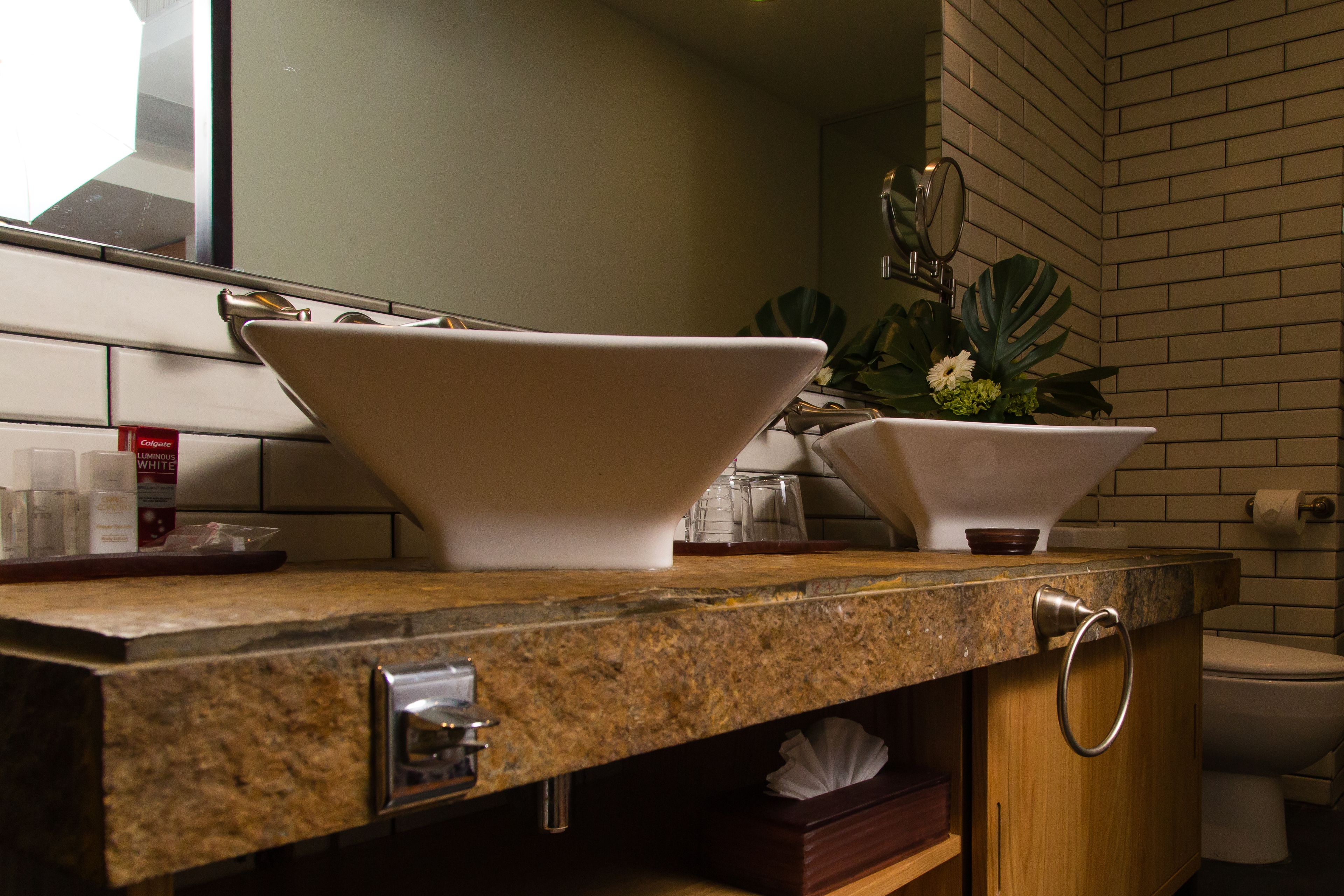 Un baño con encimera de granito, un lavabo de cerámica blanca, un espejo y un inodoro.