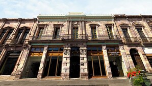Un bâtiment historique doté d’une entrée centrale, de grandes fenêtres et d’une enseigne Starbucks.