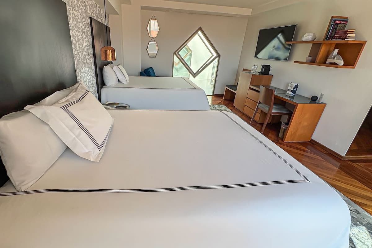Une chambre avec un grand lit, un bureau, une chaise, une télévision et une fenêtre.