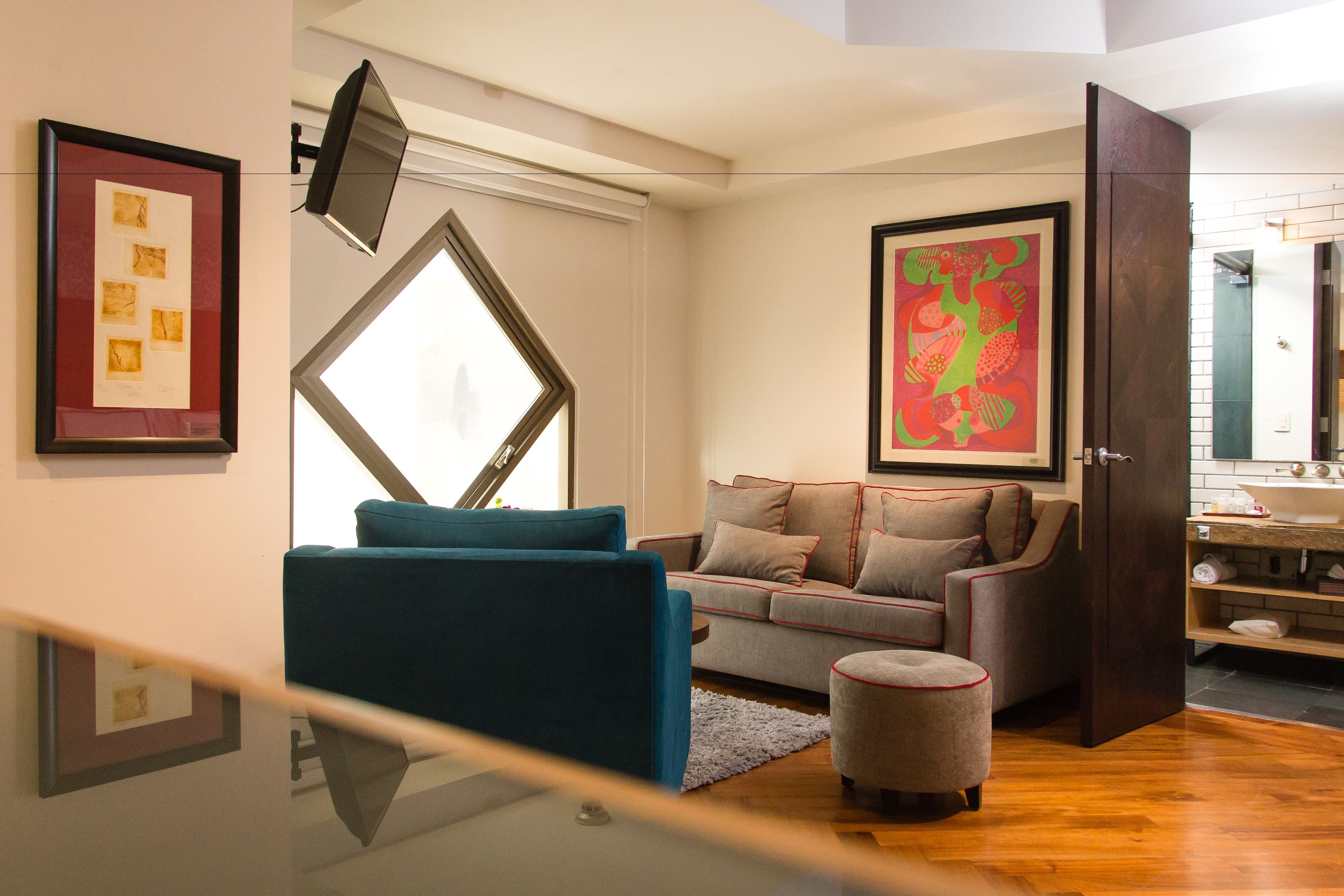 A modern living room with a sofa, ottoman, and artwork on the walls.