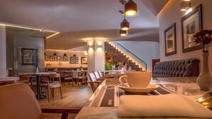 Un espace repas moderne avec une table en marbre, des sièges rembourrés et un escalier menant à un niveau supérieur.
