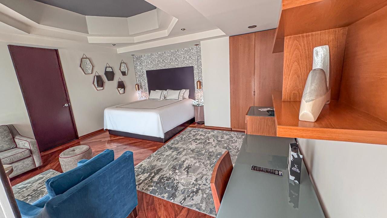 Una habitación de hotel moderna con una cama grande, un escritorio, una silla y un pequeño rincón de descanso.