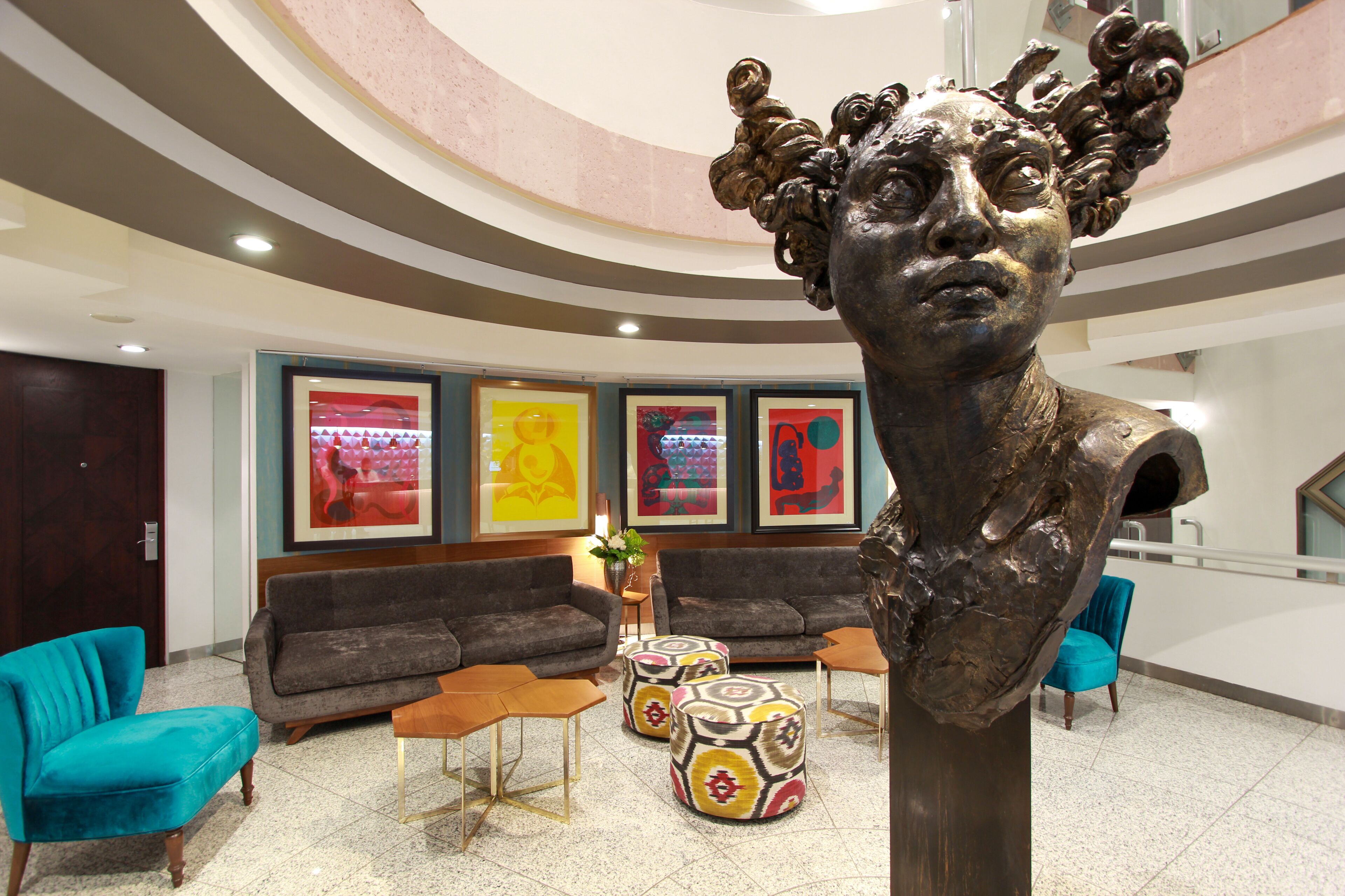 A lobby with a modern design, featuring a large sculpture, sofas, ottomans, and artwork on the walls.