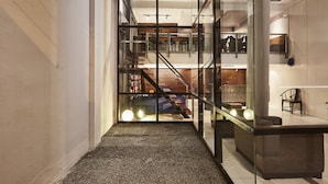 A modern interior with a glass partition, a staircase, and a seating area with a table and chairs. - Luxx at Silom (Bangkok)