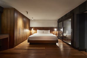 A modern bedroom with a large bed, wooden wardrobe, and a glass partition. - Luxx at Silom (Bangkok)