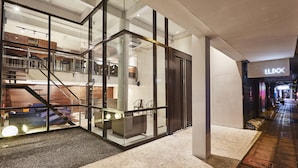 A modern interior with glass walls, a staircase, and a visible store named 'LUX'. - Luxx at Silom (Bangkok)