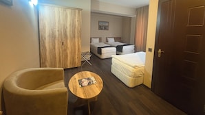 A hotel room with a bed, a chair, a small table, a wardrobe, and a door.