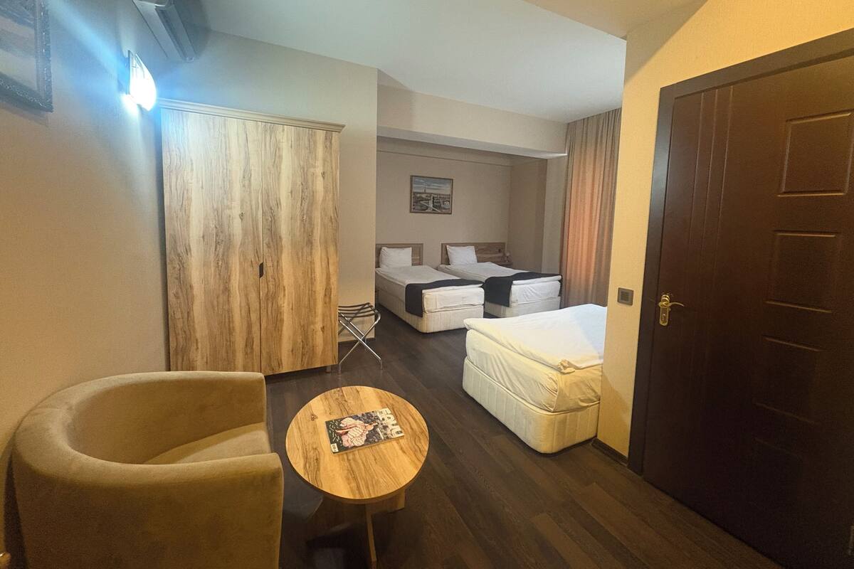 Une chambre d’hôtel avec un lit, une chaise, une petite table, une armoire et une porte.