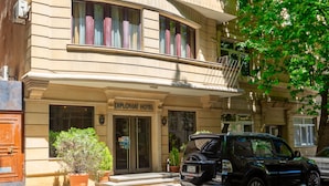 A building with a sign reading "Diplomat Hotel" and a black SUV parked in front.