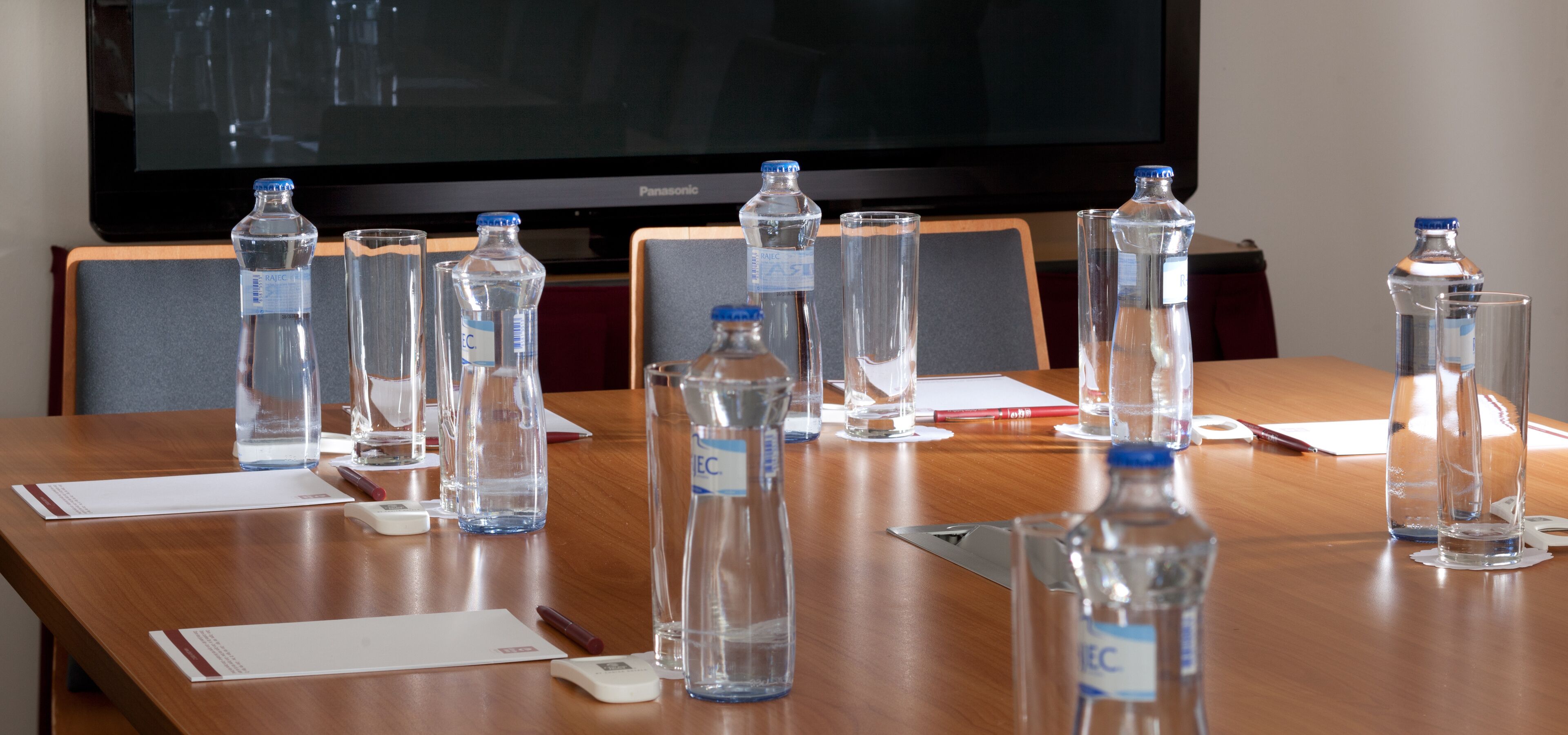 Una mesa de conferencias con botellas de agua, vasos y documentos.