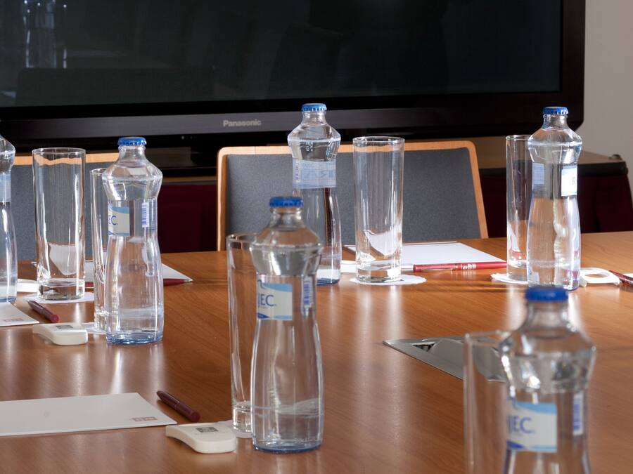 Una mesa de conferencias con botellas de agua, vasos y documentos.