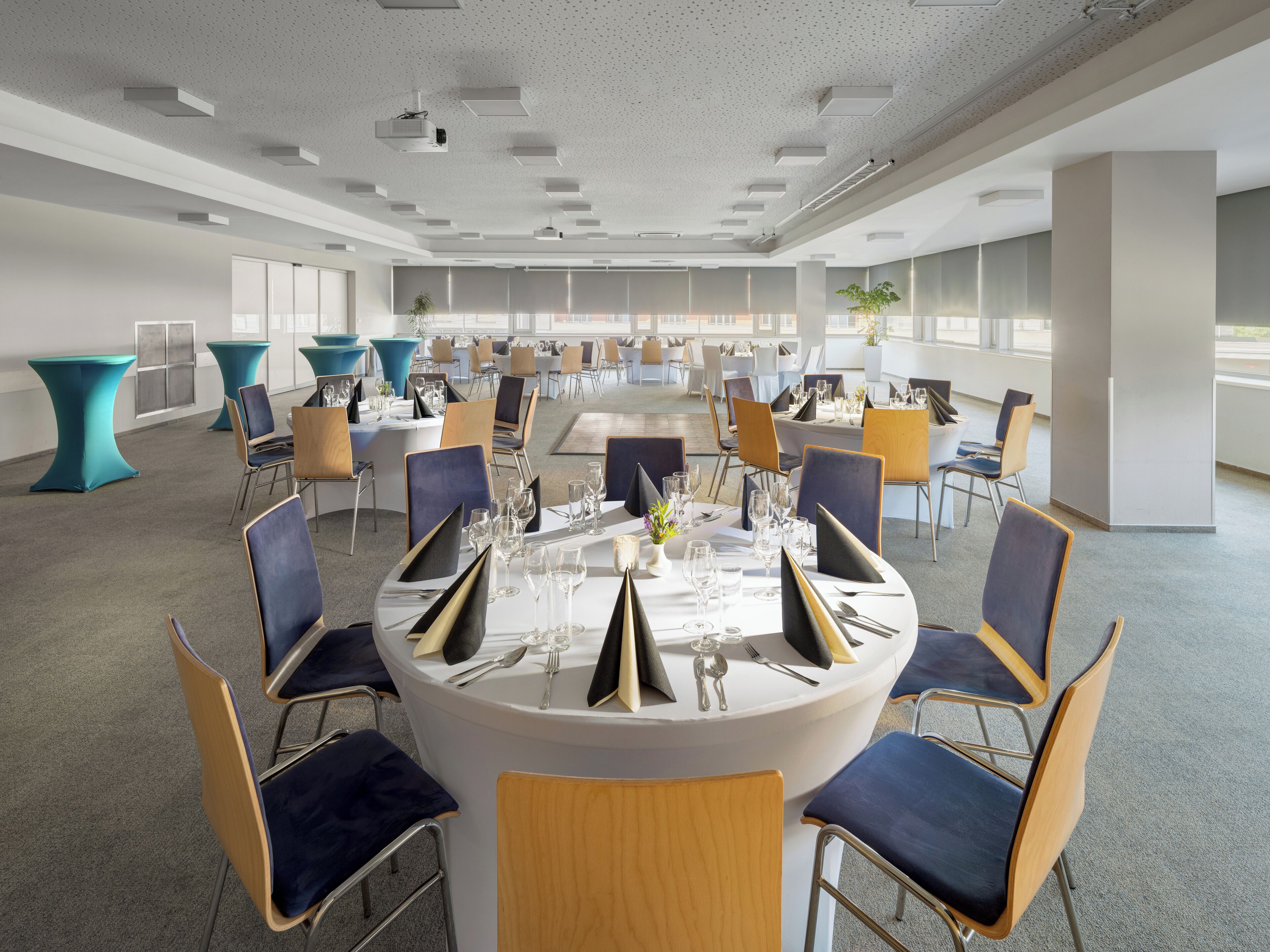 A conference room with round tables, chairs, and a ceiling projector.