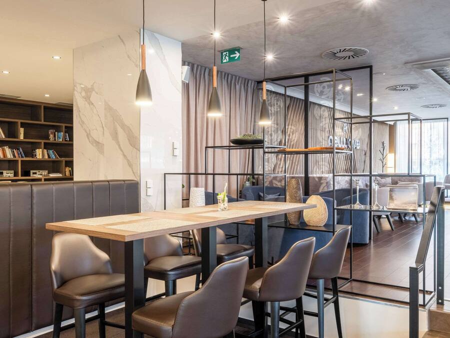 En moderne restaurant med et langt træbord, læderstole og en reol fyldt med bøger.