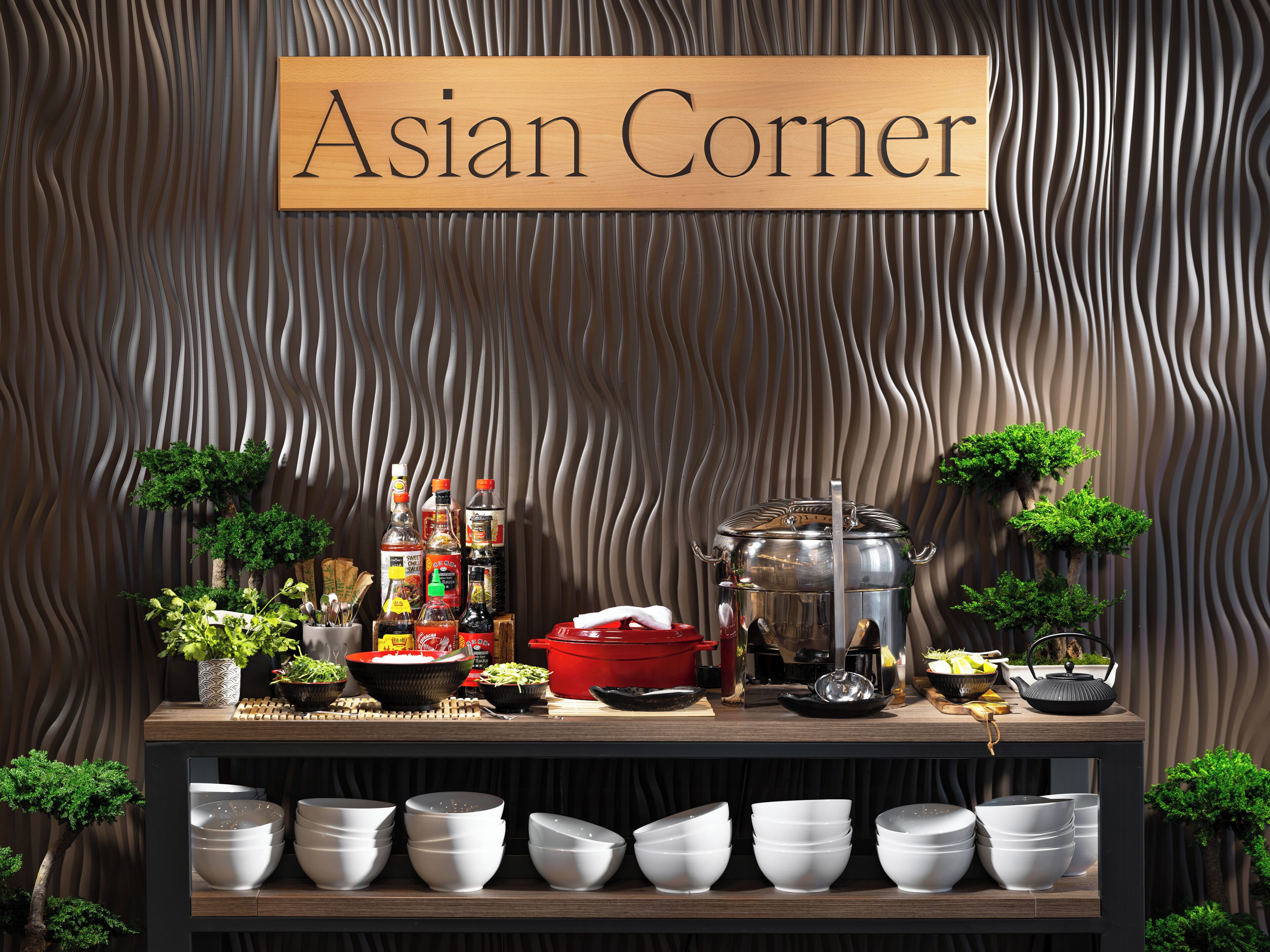 A kitchen area with a sign reading 'Asian Corner,' featuring cooking utensils, pots, and Asian-style plants.