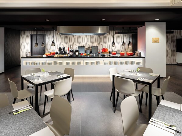 A modern restaurant with a central counter, multiple dining tables, and chairs.